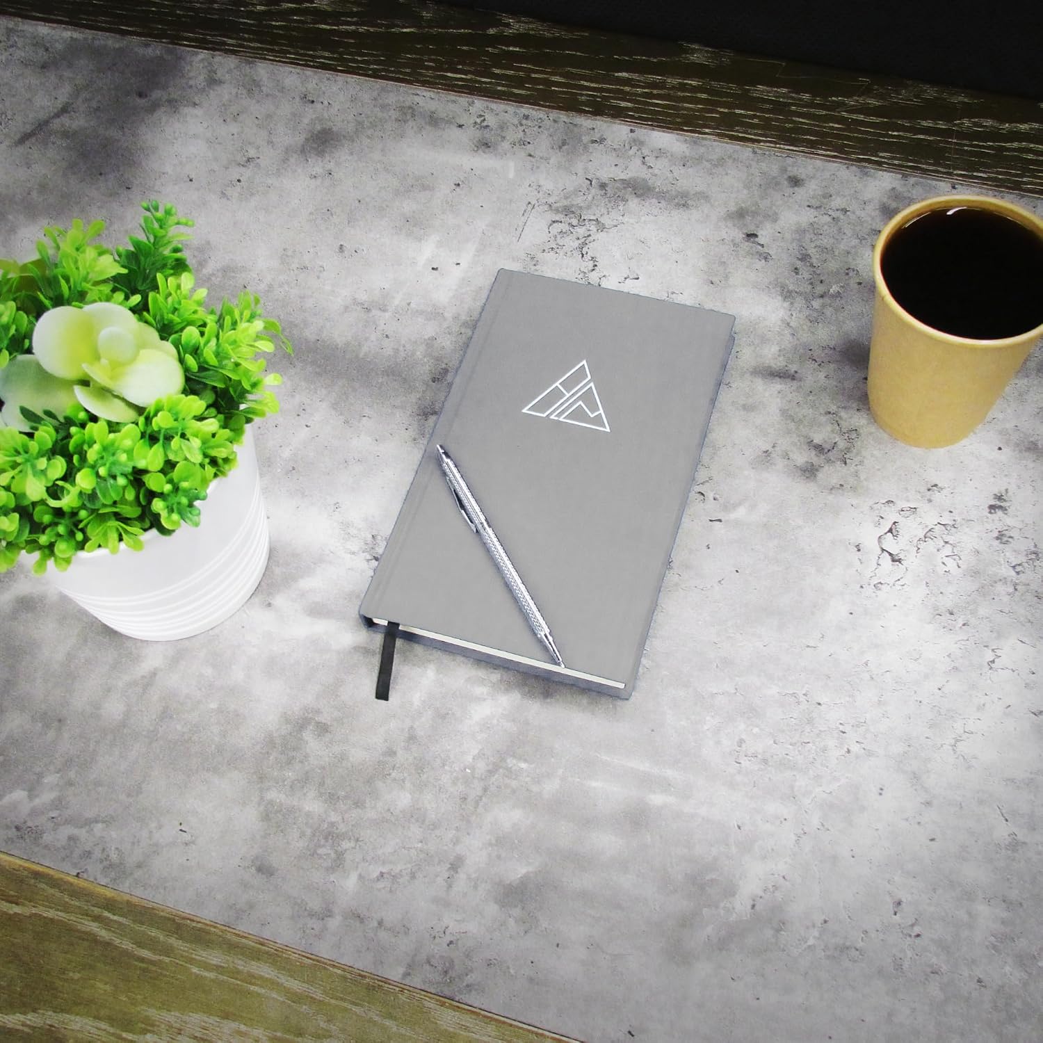 Gray journal closed on a concrete desk with a silver pen